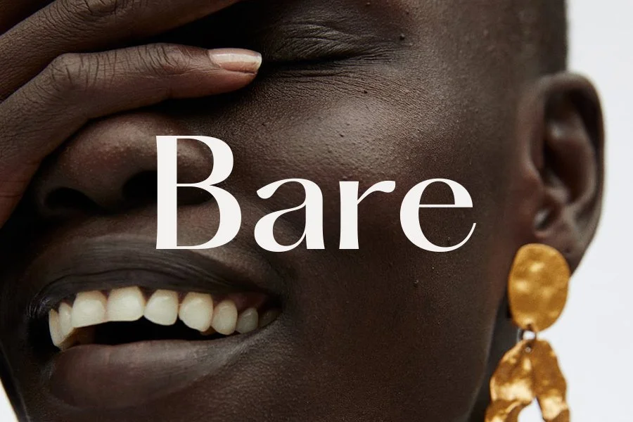 Primer plano de una persona sonriendo, con una mano cubriendo parcialmente su cara y usando un pendiente dorado. Texto "Bare" superpuesto en el centro de la imagen.