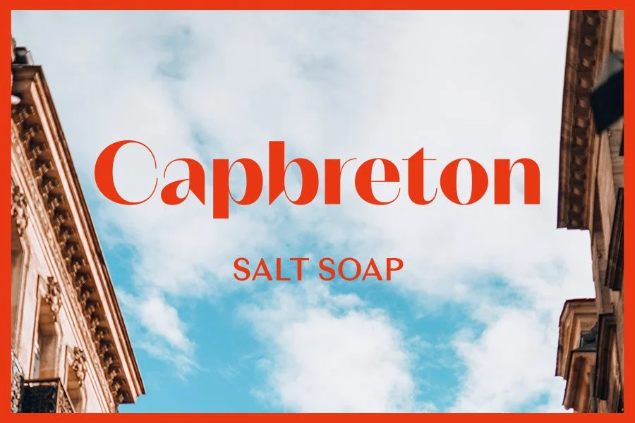 Cielo con nubes y texto "Capbreton Salt Soap" con edificios a los lados. Branding por Agosto Creative Studio. Branding y diseño de identidad visual y logotipo de marca de skincare y jabones.