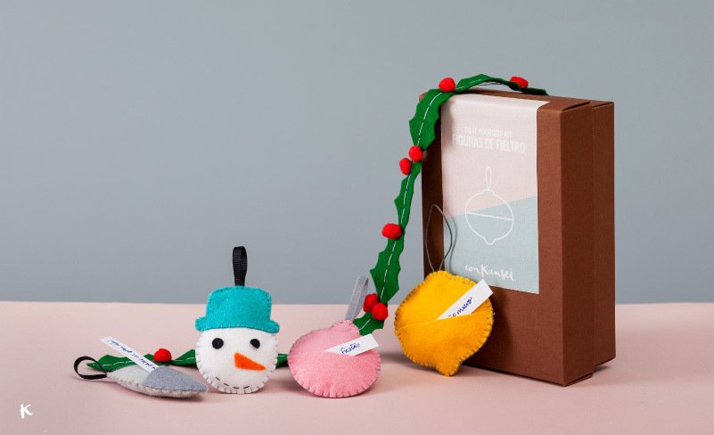 Conjunto de adornos navideños y caja de regalo decorada con un moño verde y pasas rojas.