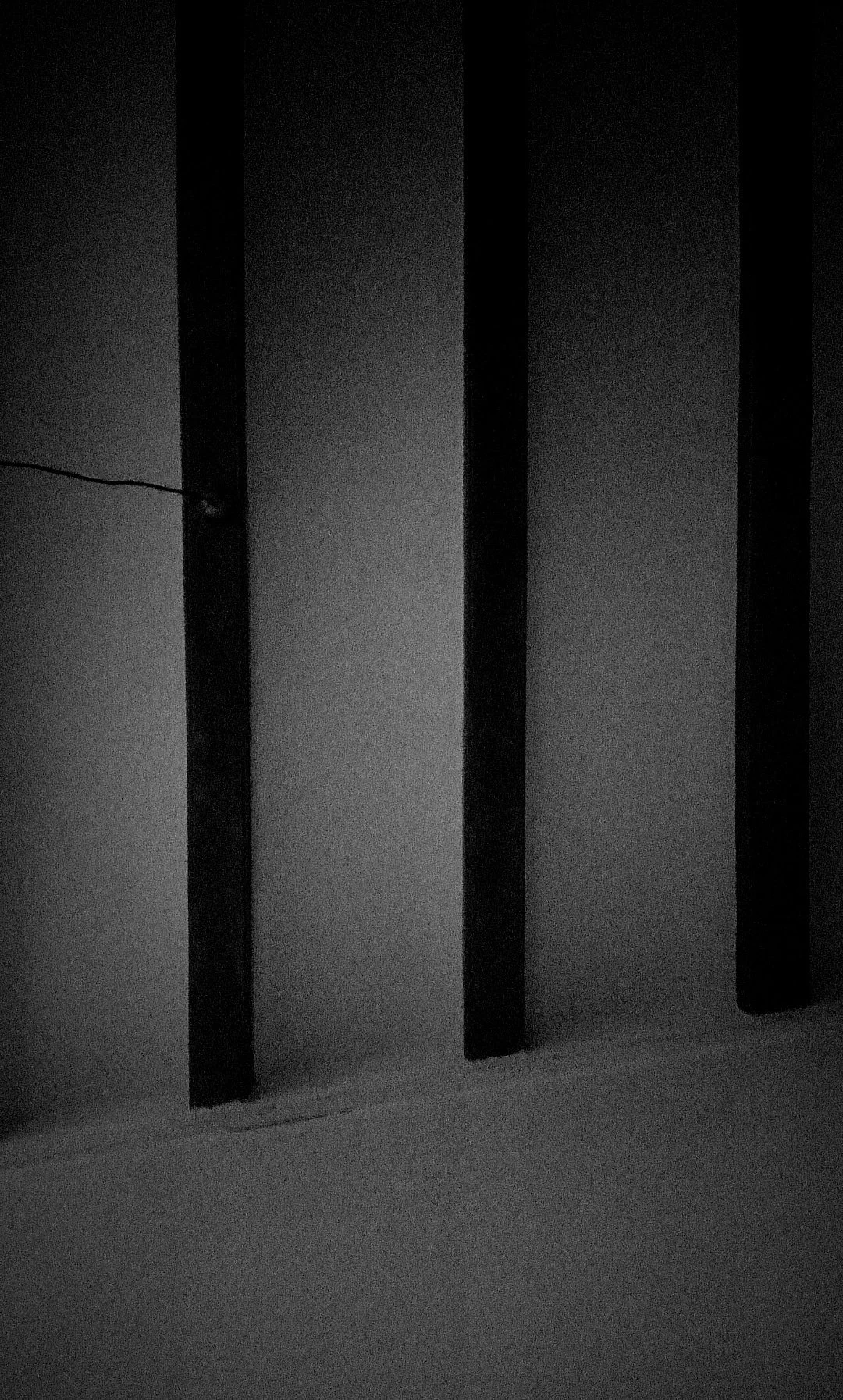 Imagen en escala de gris de varias vigas o listones en una pared, con una línea eléctrica visible en la parte izquierda.