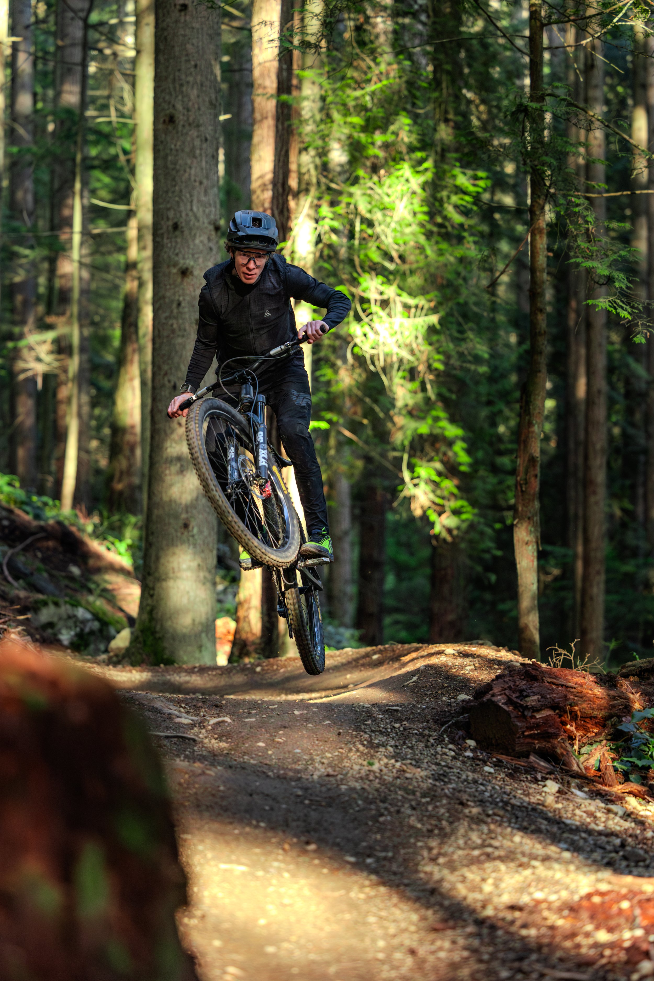 Mountain biker performing a jump on a forest trail