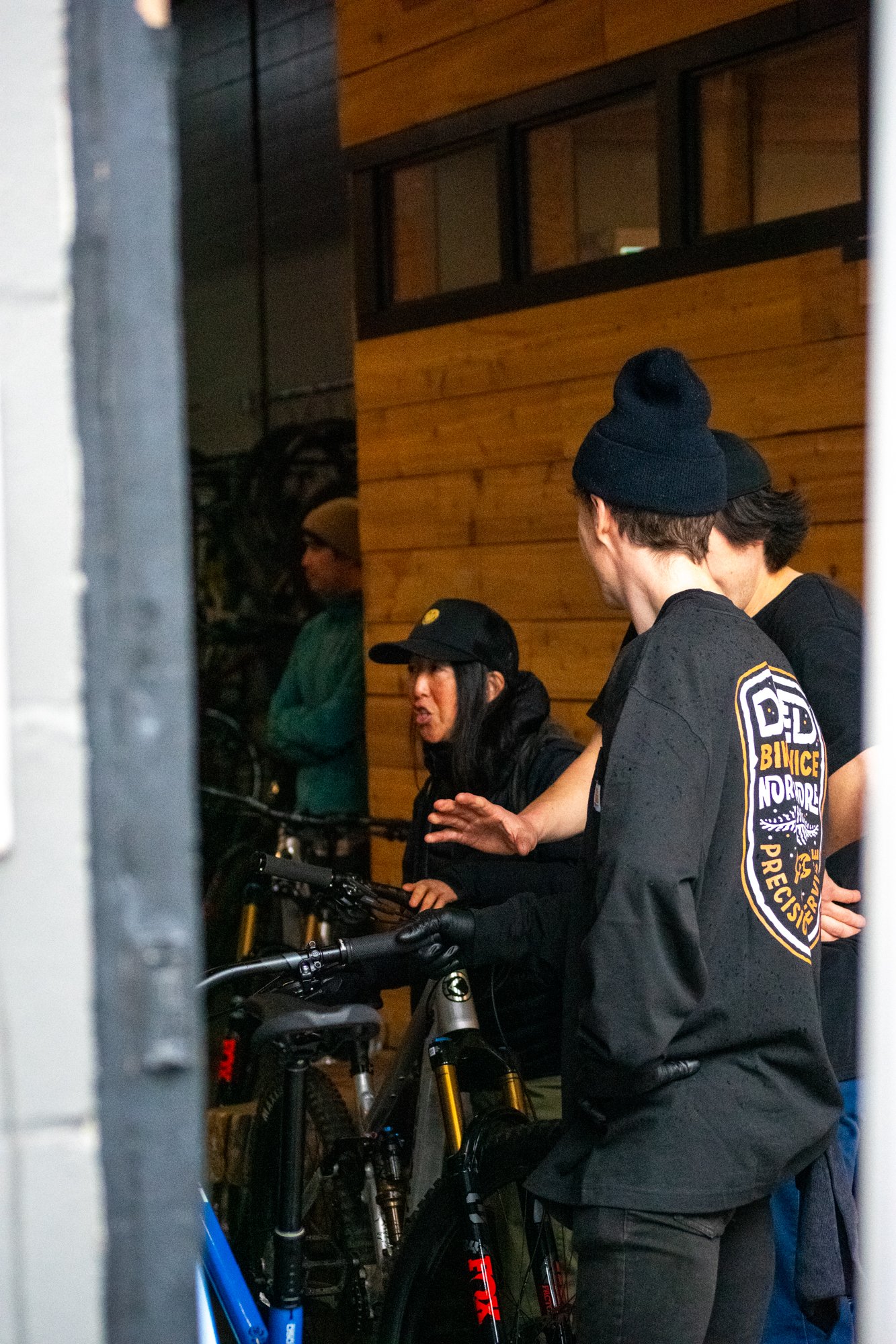 Group of people with bicycles in a workshop, discussing or interacting with the bikes.