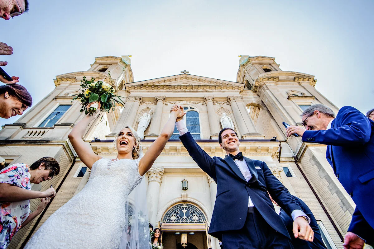 Bride and groom exit the church as guests cheer