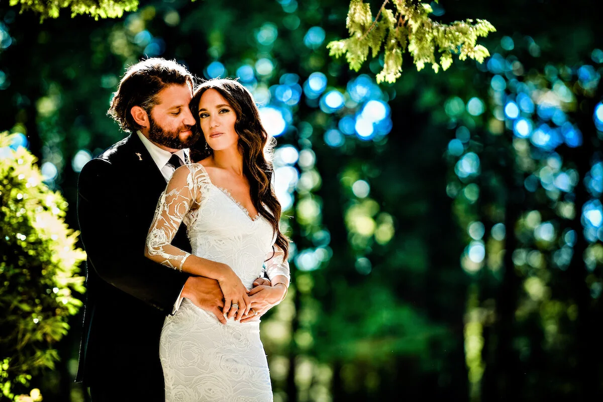 Groom embraces bride with nature backdrop
