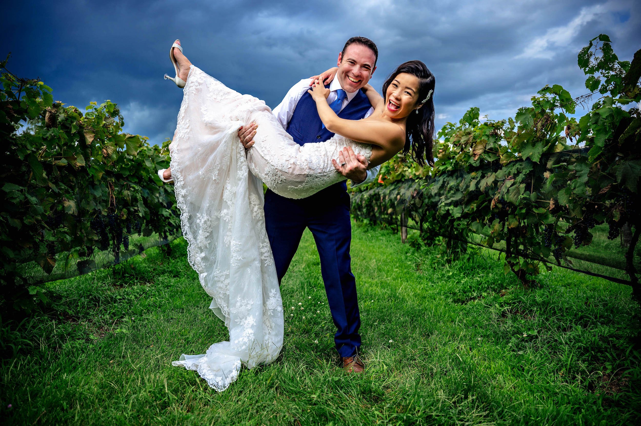 Groom holds bride in his arms while they laugh