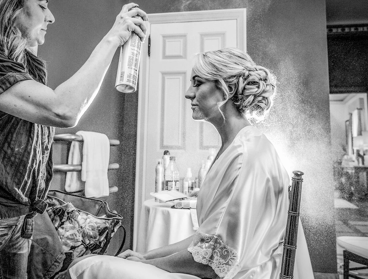 Hairstylist applying brides' hairspray