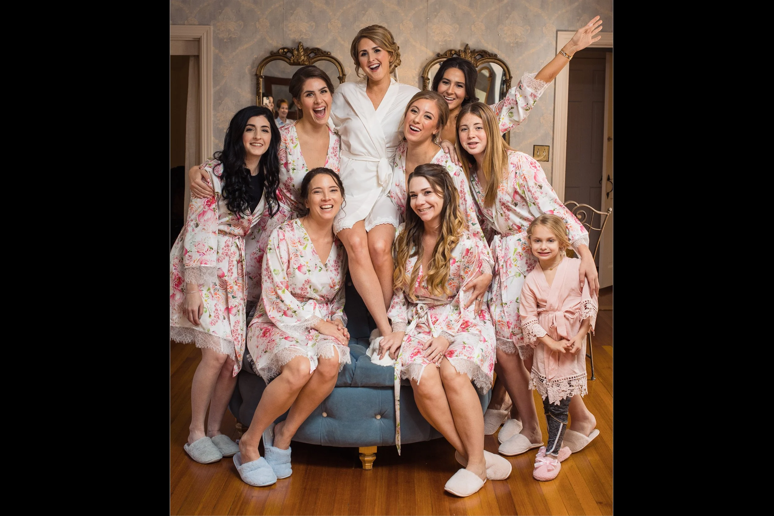 Bride poses with bridesmaids and flower girl in bridal suite