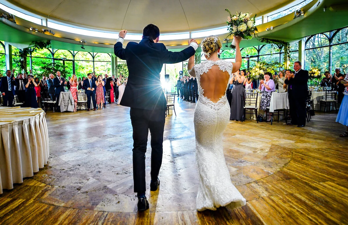 Bride and groom enter wedding reception as crowd cheers