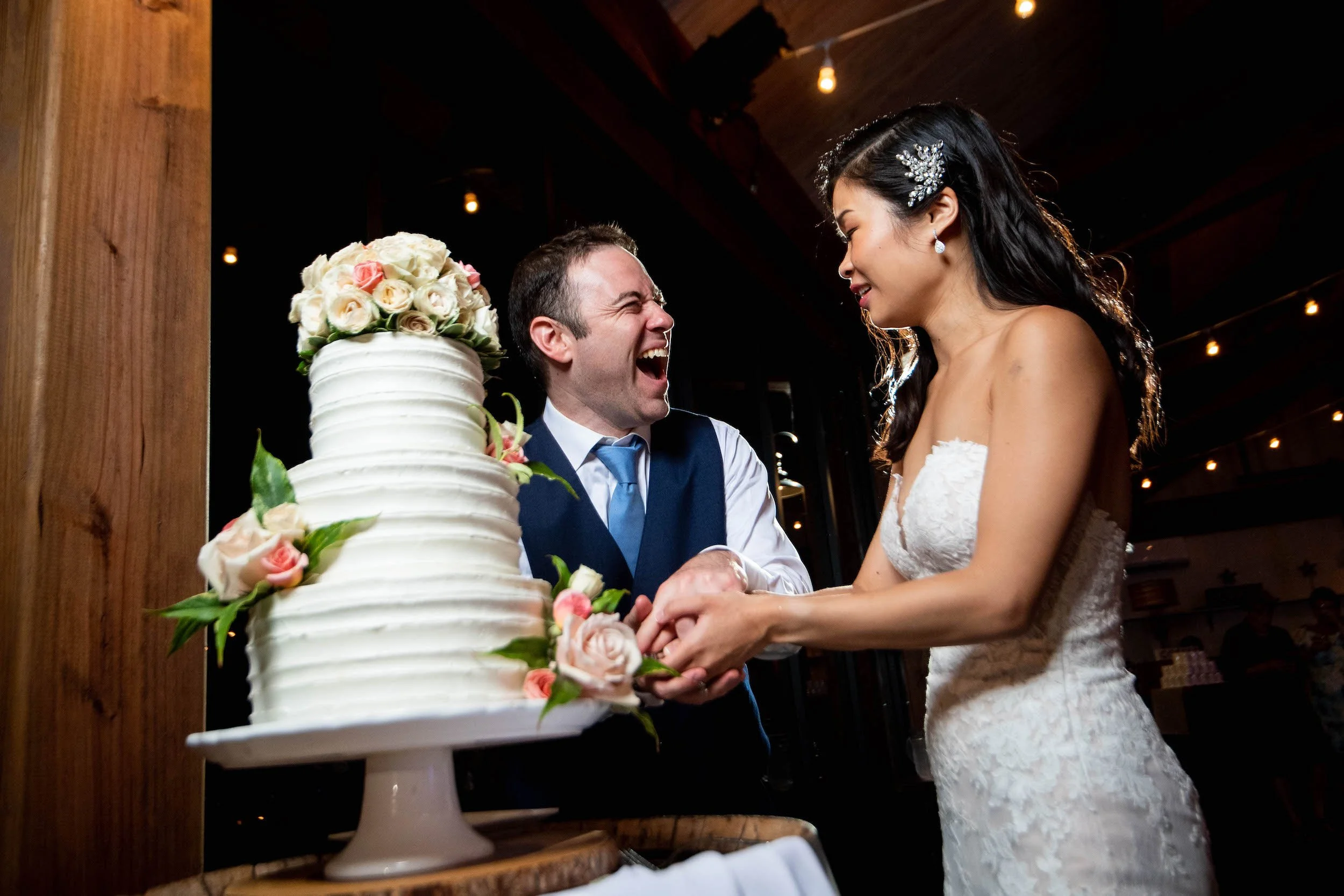Bride and groom cut cake with silly faces
