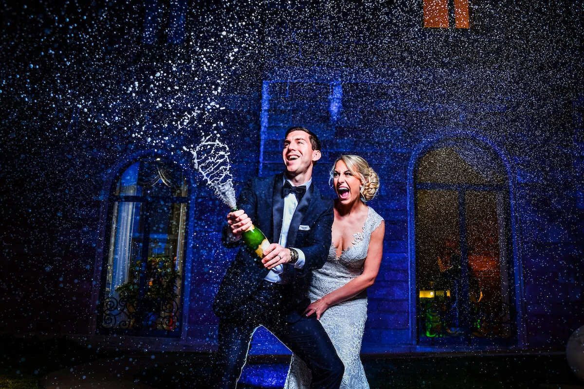 Bride and groom celebrate as they open shaken champagne bottle