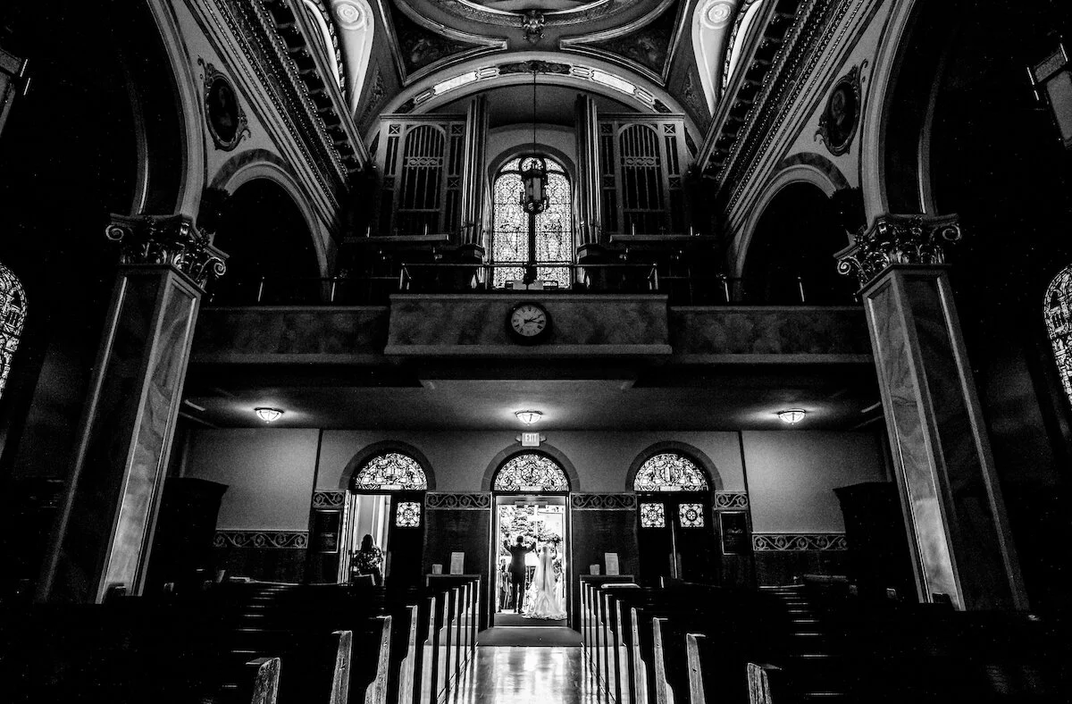 Bride and groom hold hands at church entrance