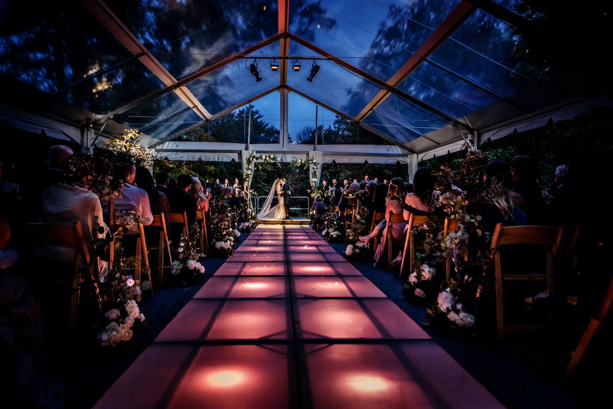 Aisle view of bride and groom kissing at ceremony