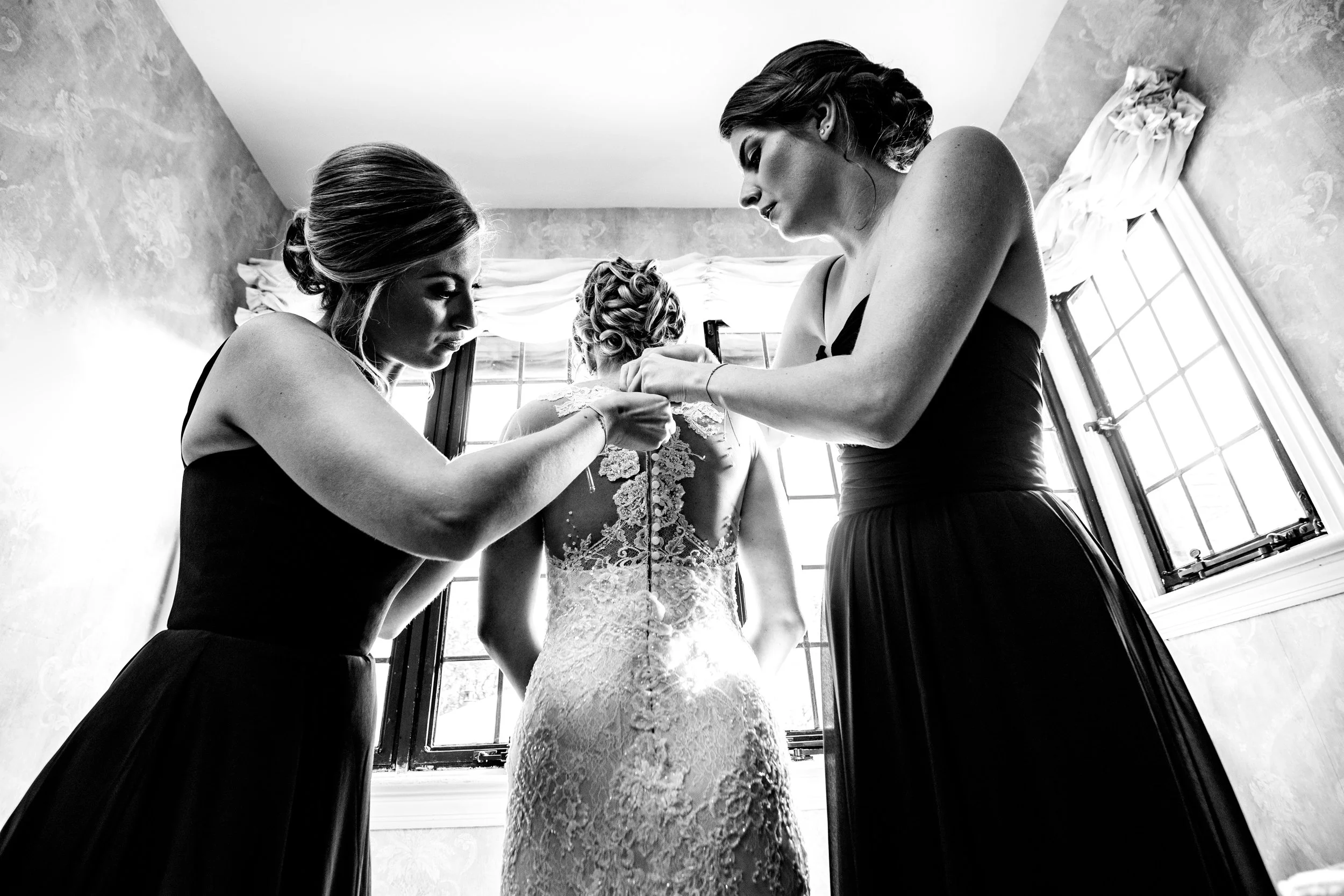 Bridesmaids zipping up bride's dress