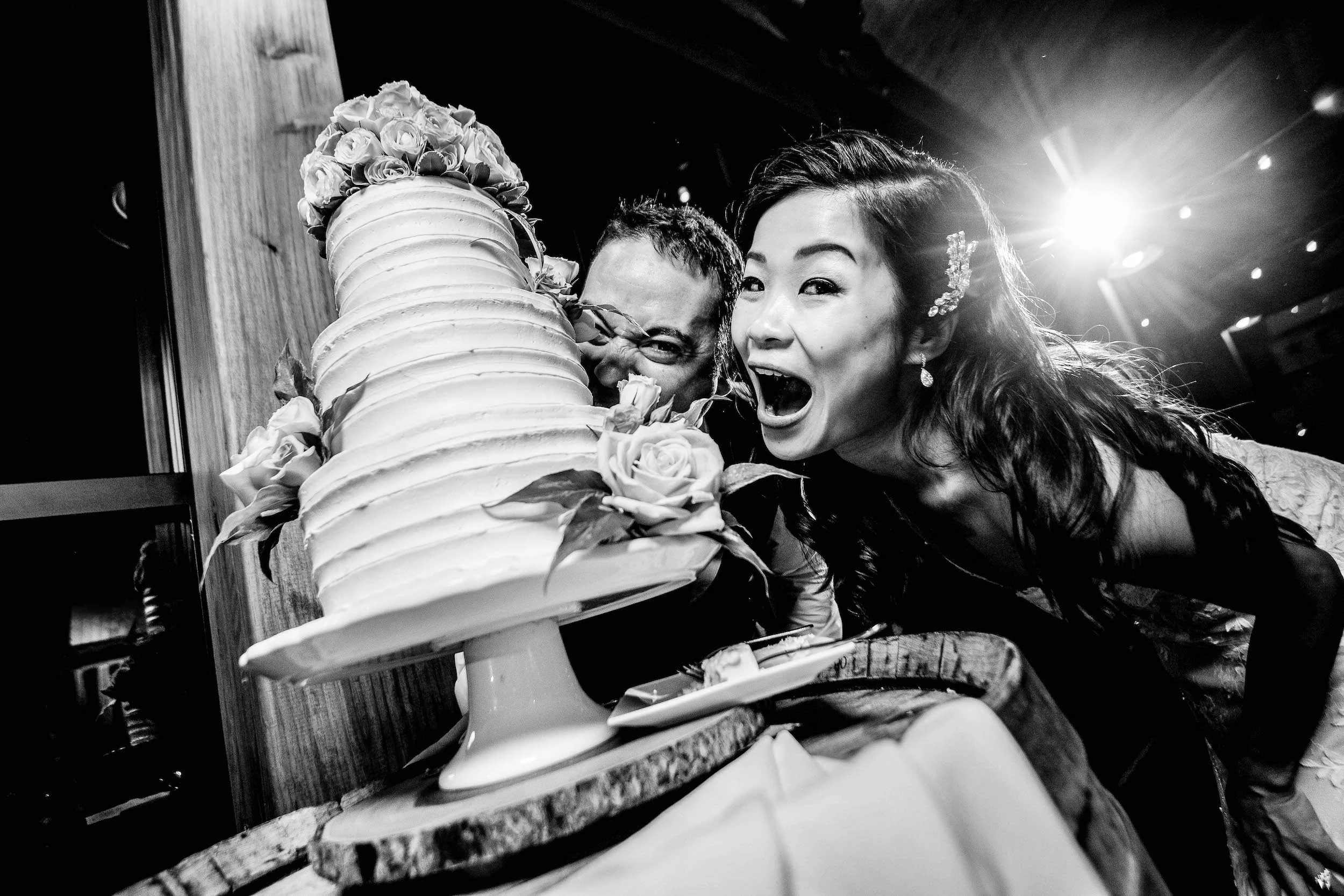 Bride and groom pretend to eat cake with funny faces
