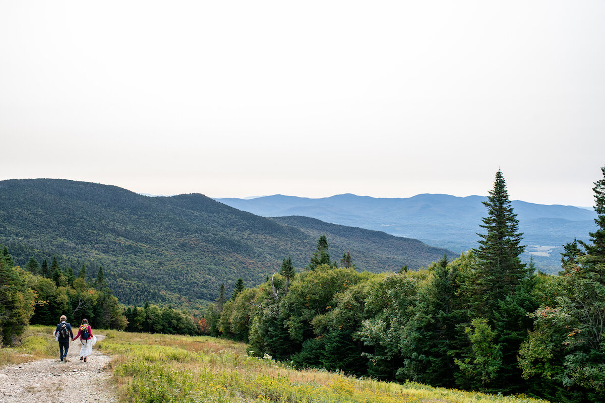 Panoramic of bride and groom on hiking trail with Vermont mountainside in view