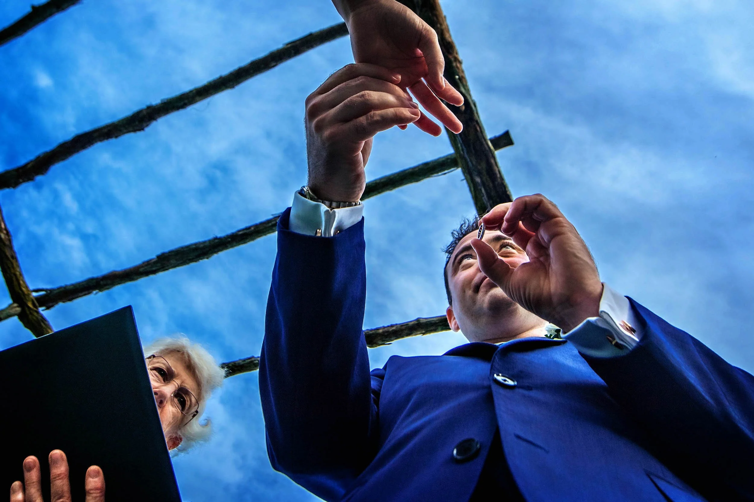 View from below of groom putting ring on his bride's hand