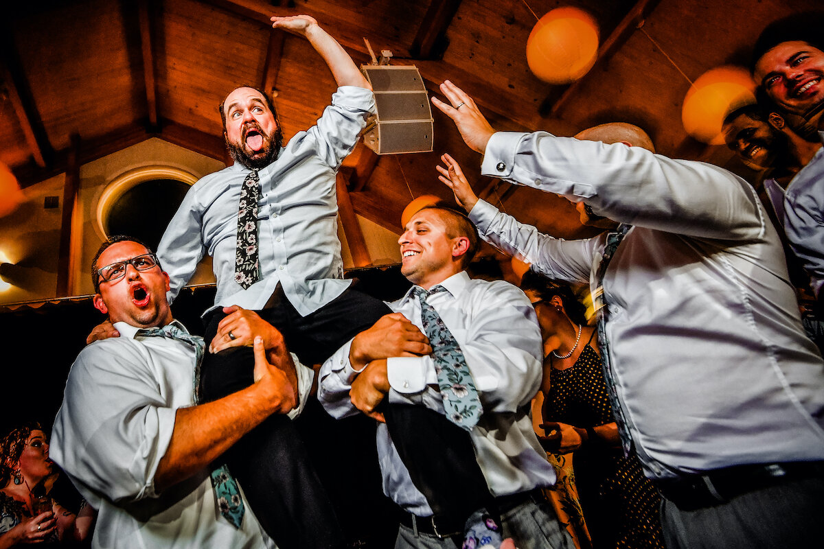 Groomsmen jump and celebrate on dance floor