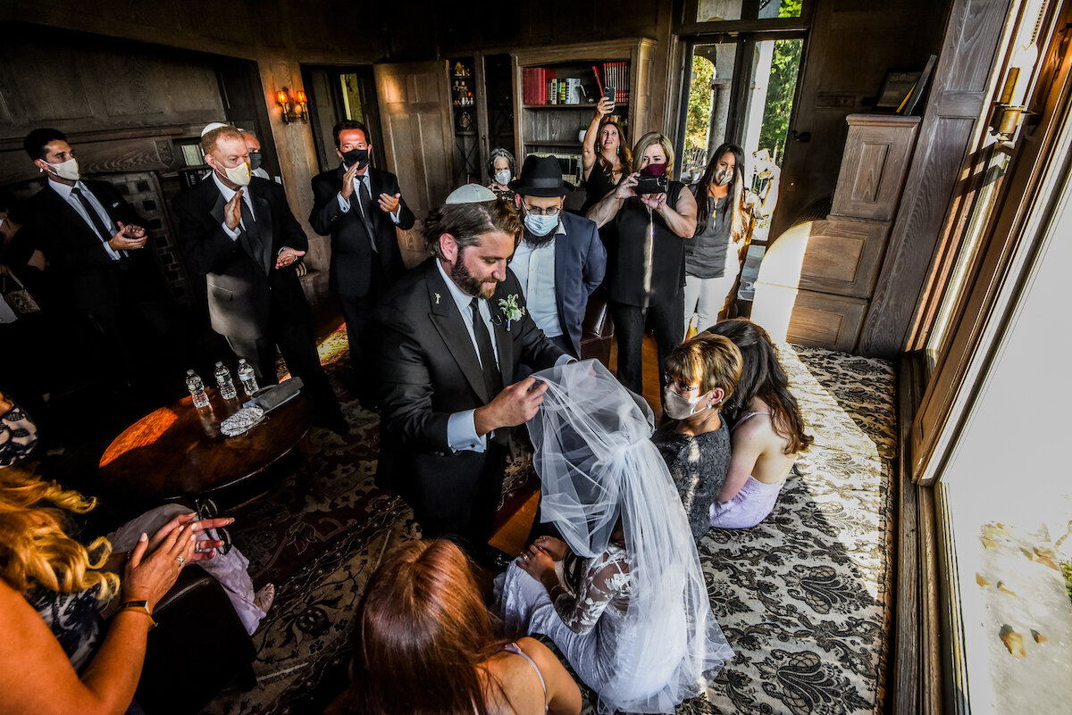 Groom takes veil off bride as guests gather