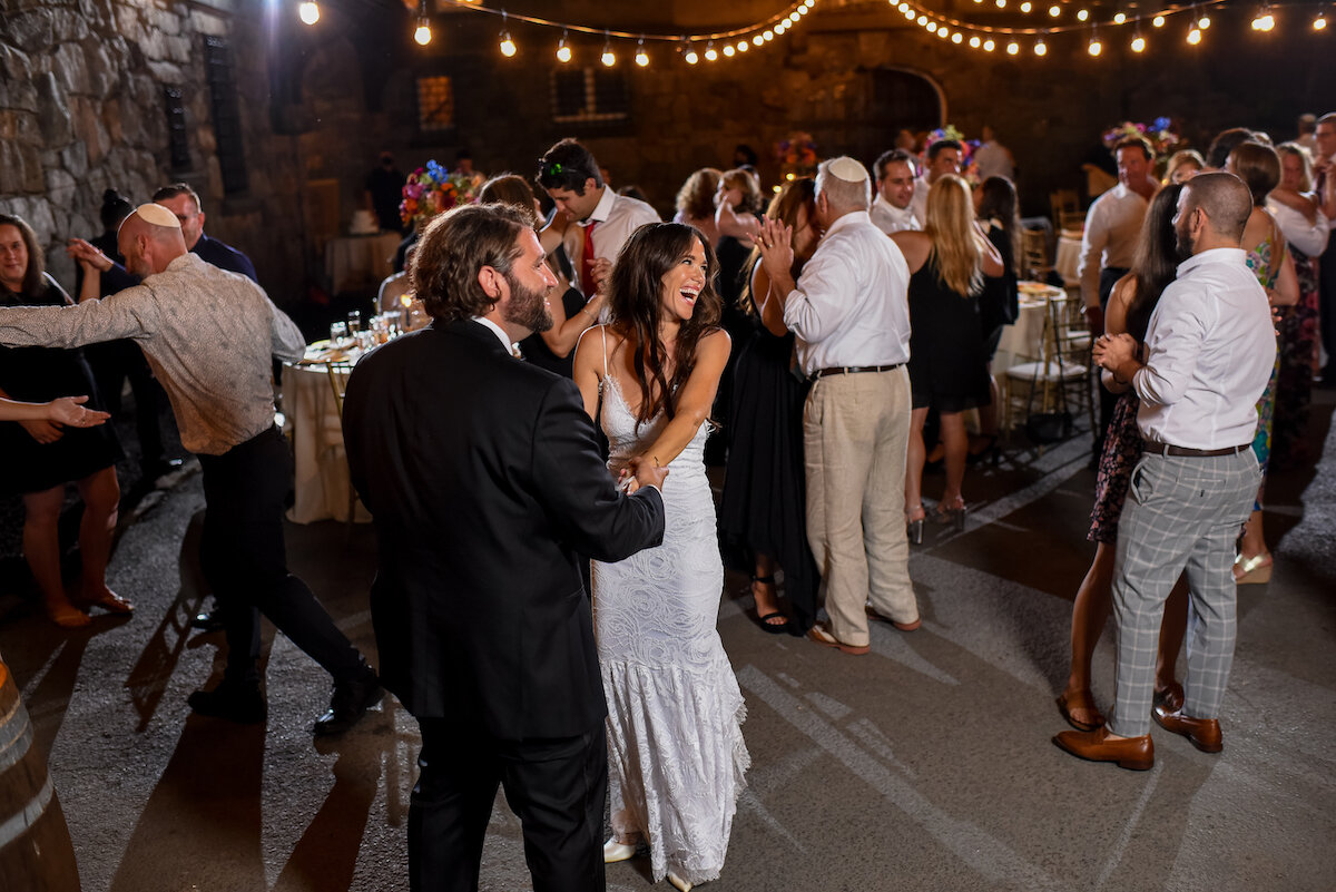 Bride and groom dance with guests on dance floor