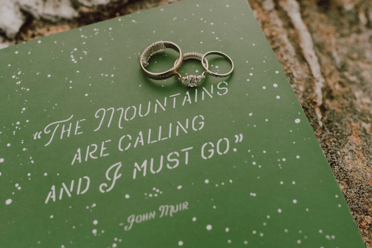 Rings laid on postcard with quote 'The mountains are calling and I must go'