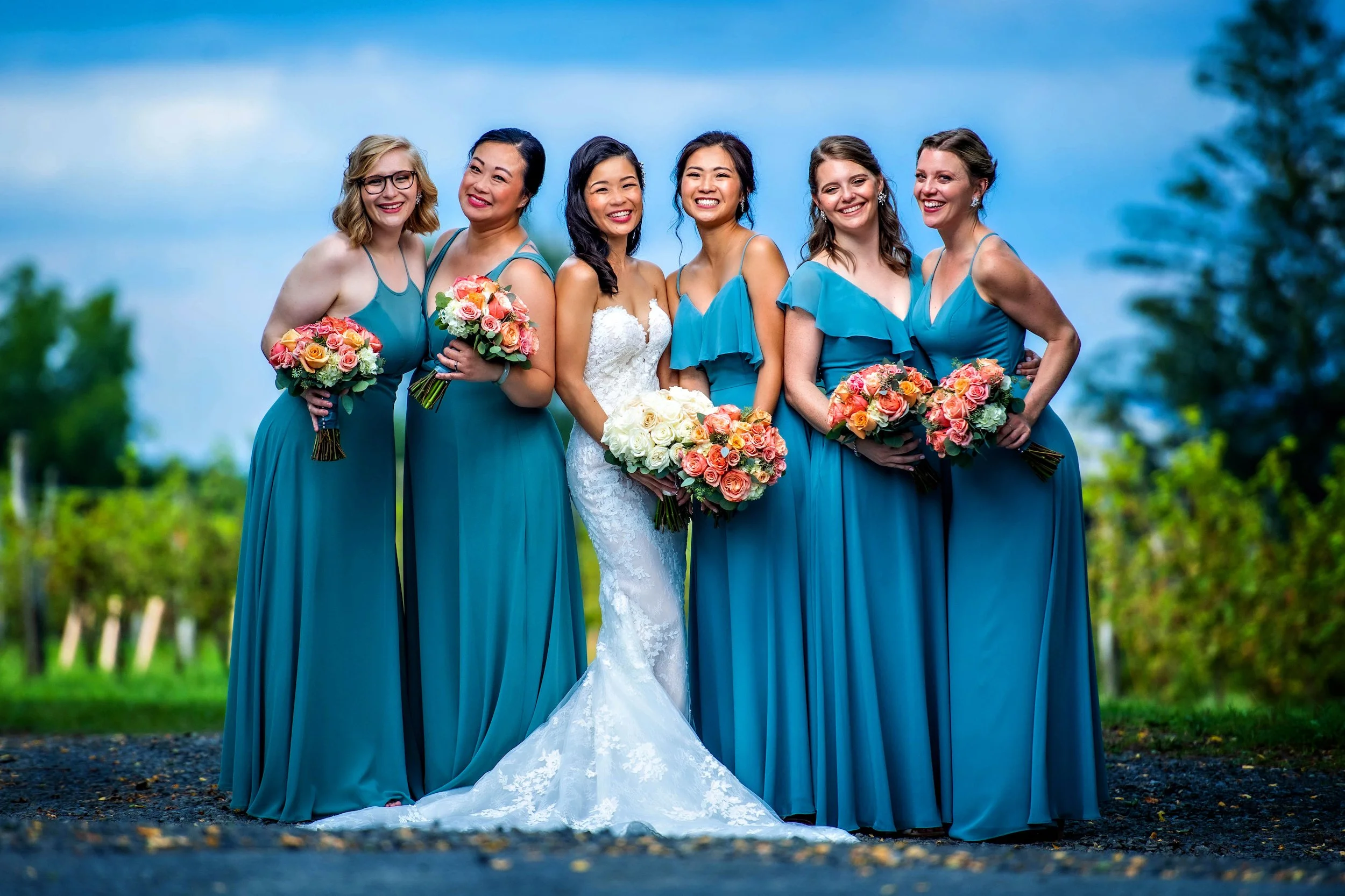 Brides and bridesmaids pose outdoors at venue