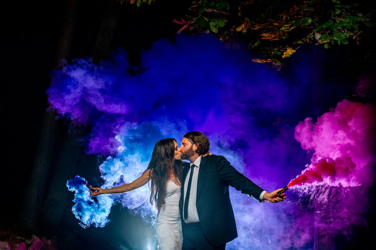 Bride and groom kiss as they open pink and purple color canisters