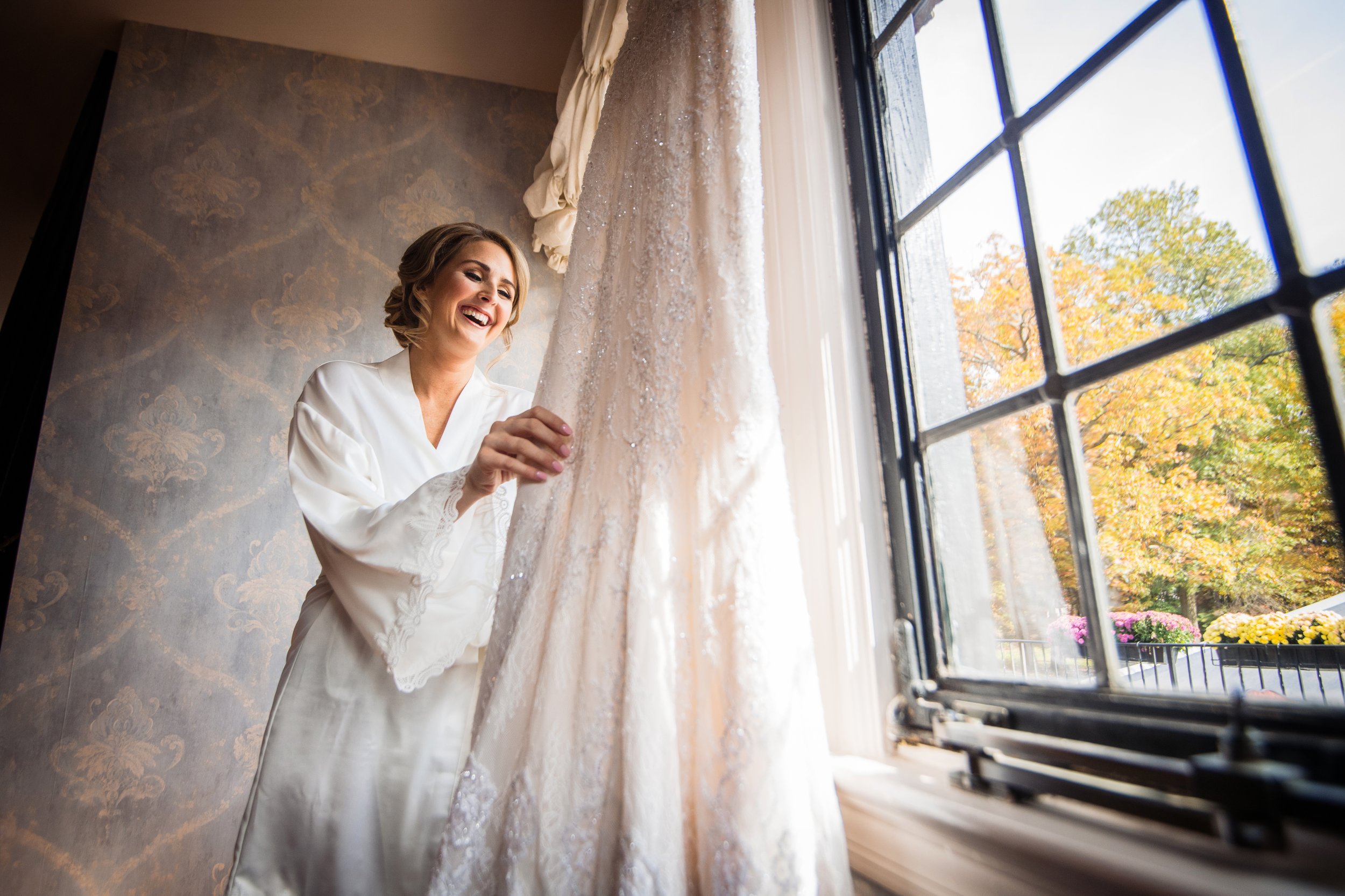 Bride laughs while holding wedding dress