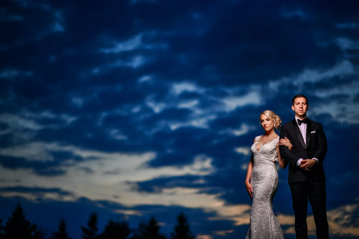 Bride and groom pose with stormy sky background