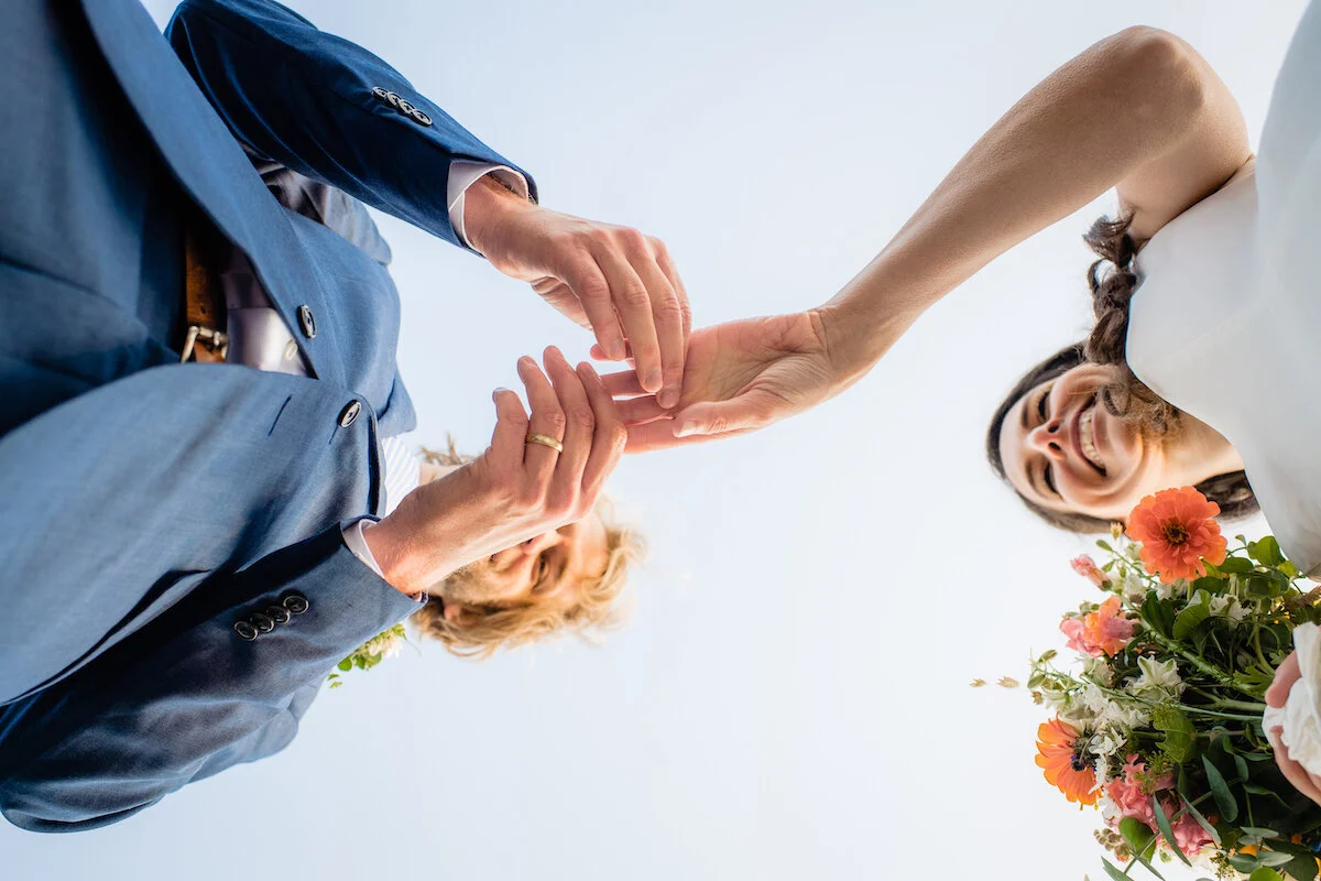 View from below of groom placing the ring on bride's wedding finger