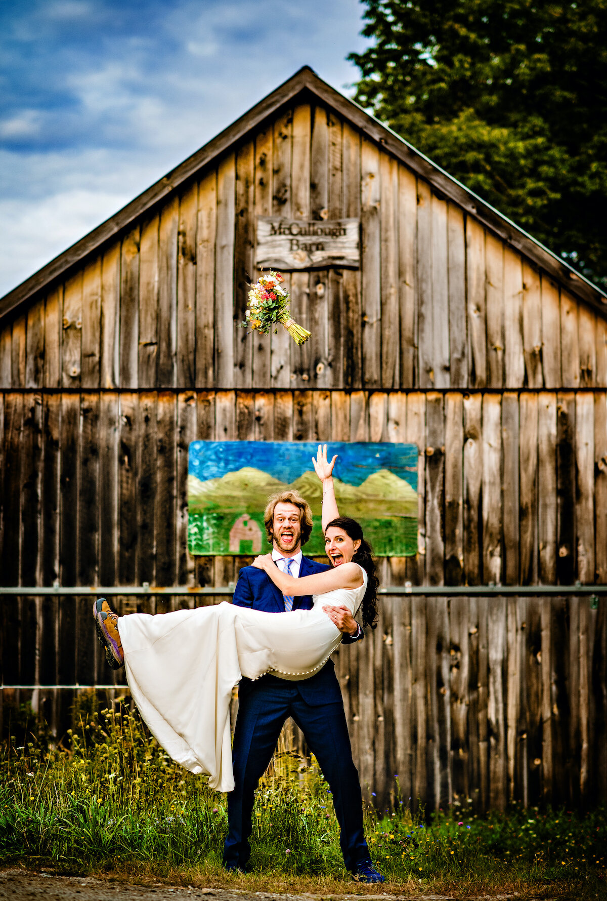 Groom holds his bride in front of stained barn entrance