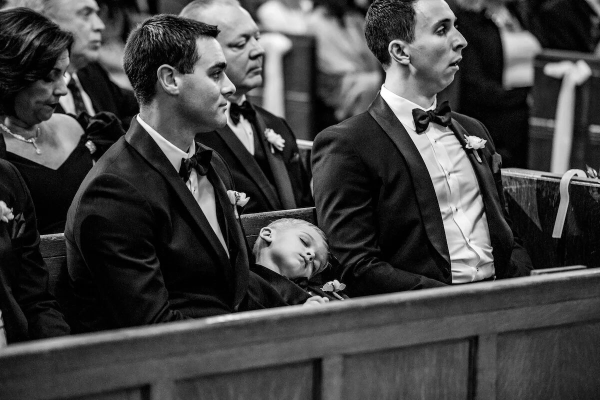 Little boy sleeps during ceremony next to groomsmen