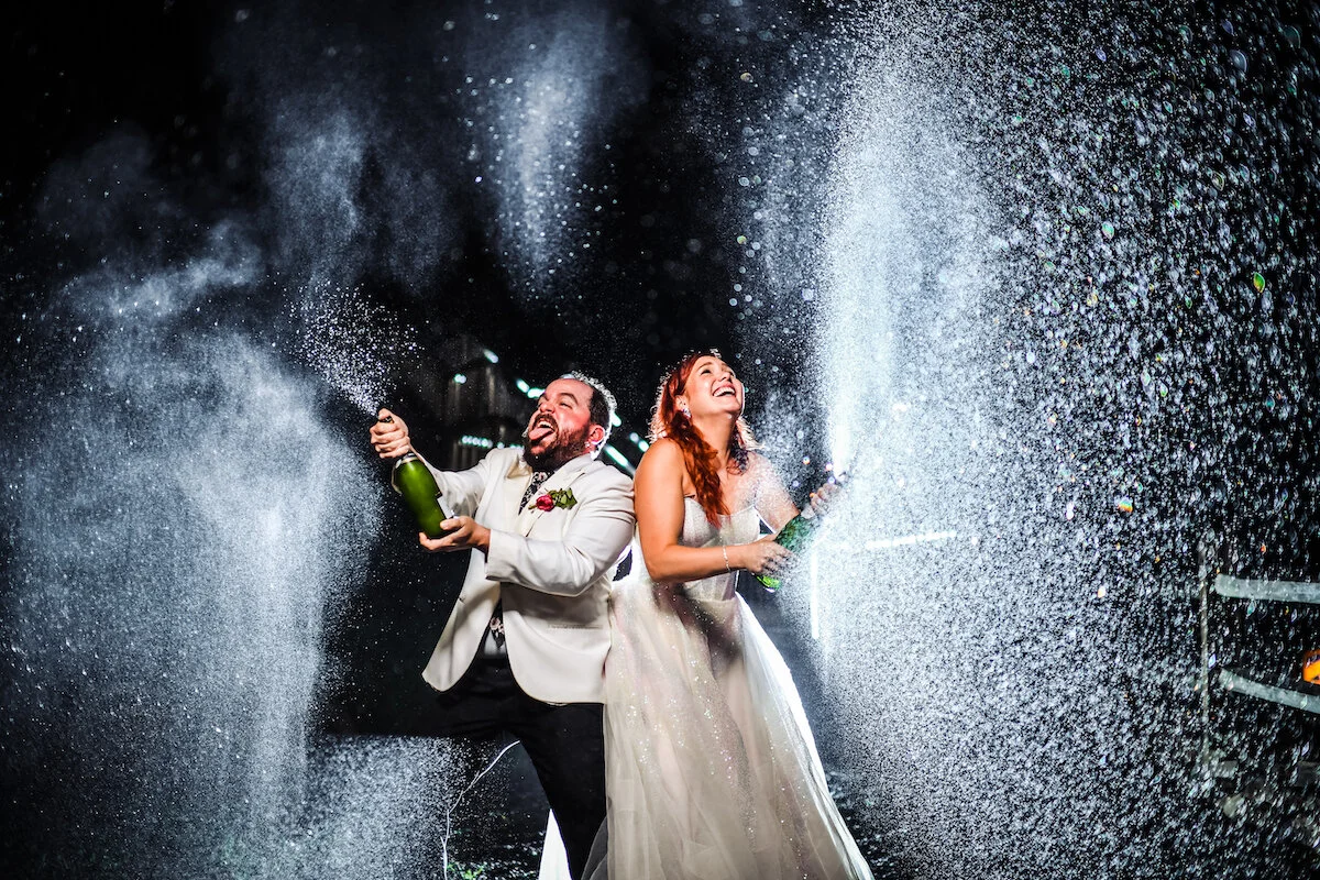 Newly married couple pops champagne bottle spraying everywhere