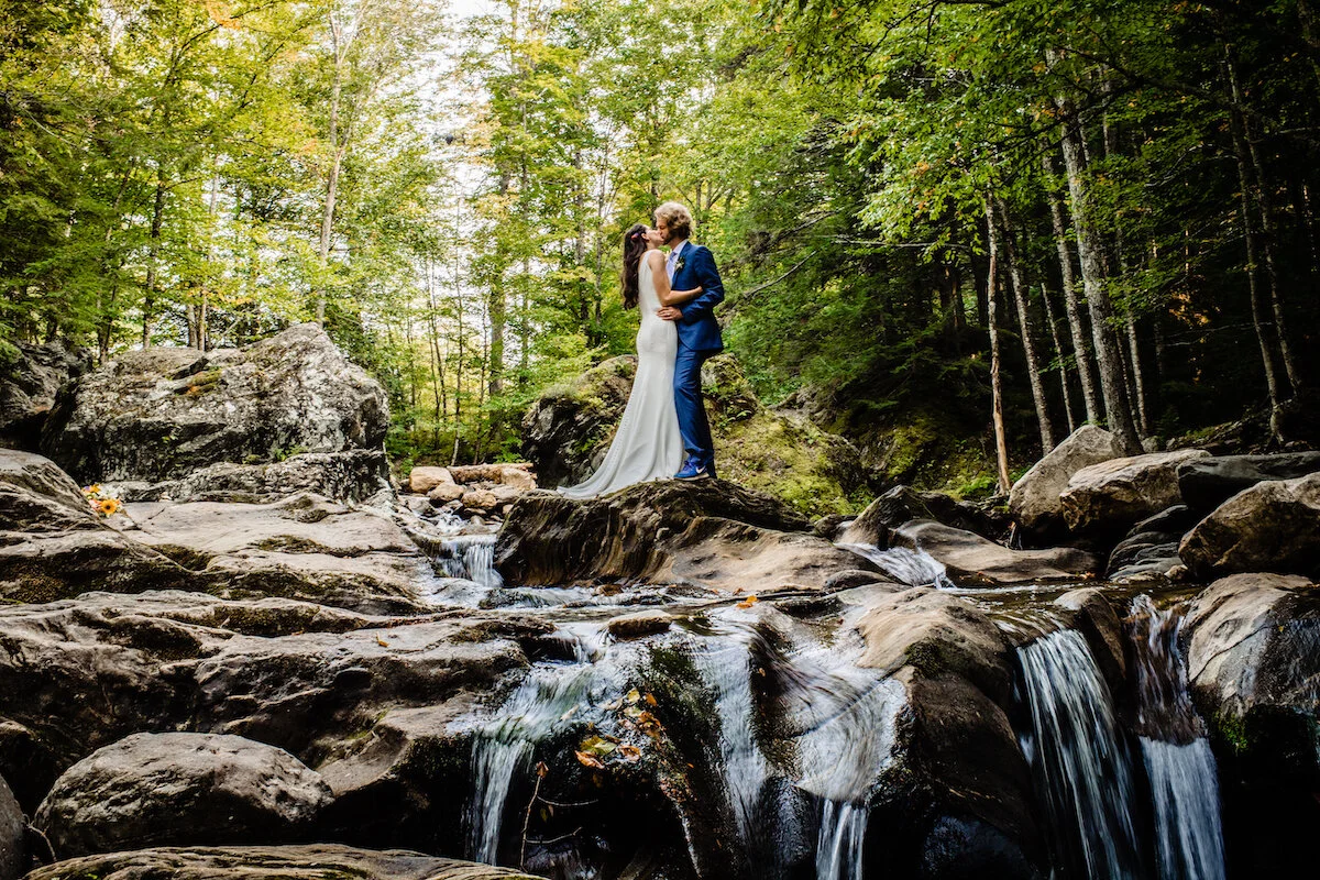 Bride and groom intimate kiss in forest creek
