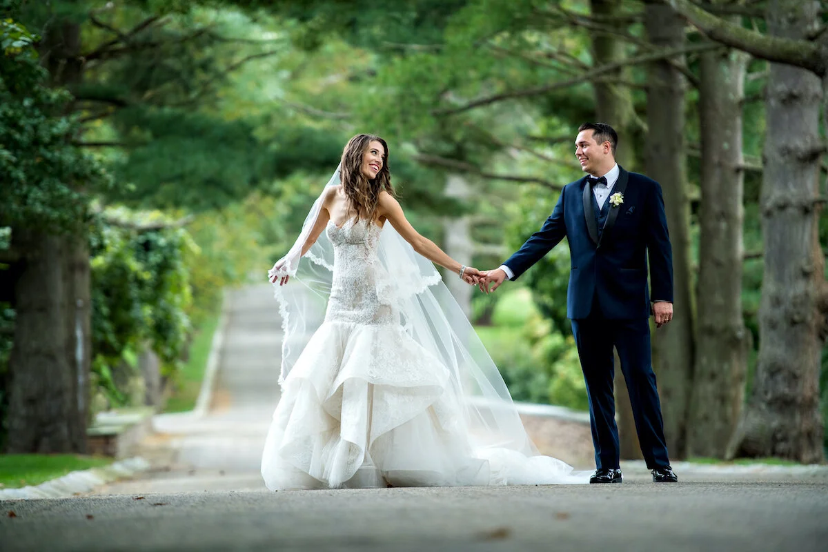 Bride twirls with groom on road surrounded by blooming trees