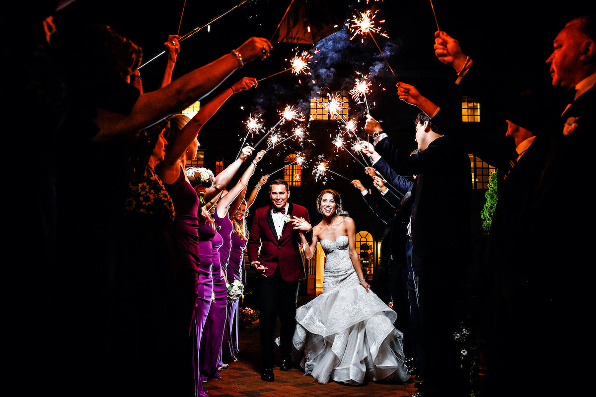 Guests light sparklers as bride and groom depart