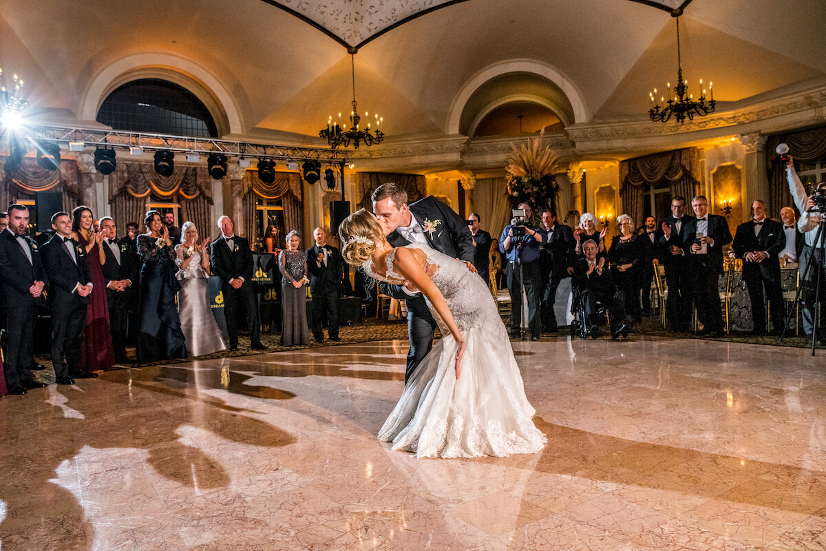 Bride and groom share a kiss during first dance as guests celebrate