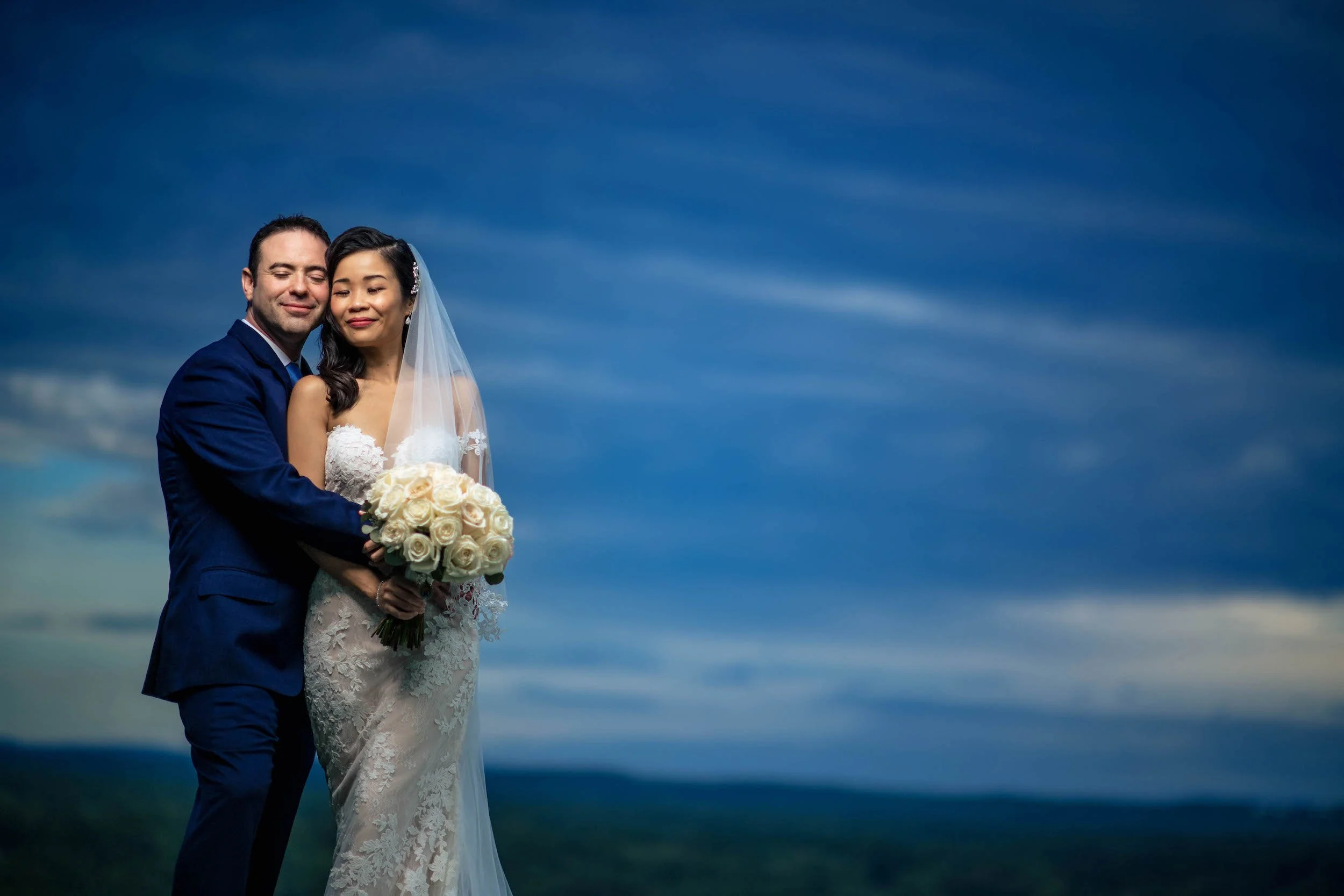 Bride and groom pose in front of blue skies
