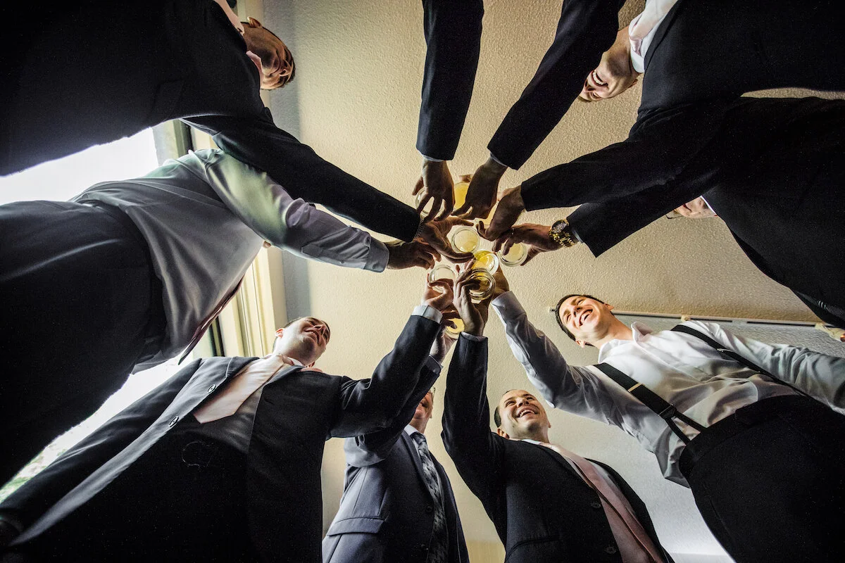 Shot from below of groomsmen toasting with personalized glasses