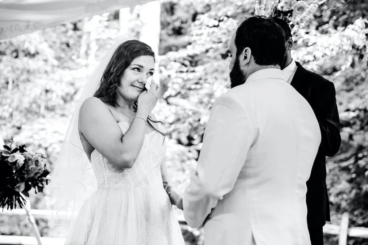 Bride wipes tears at alter as groom holds her hand
