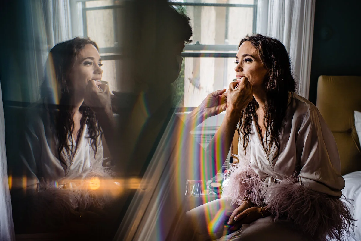 Mirror image of makeup artist applying bridal makeup