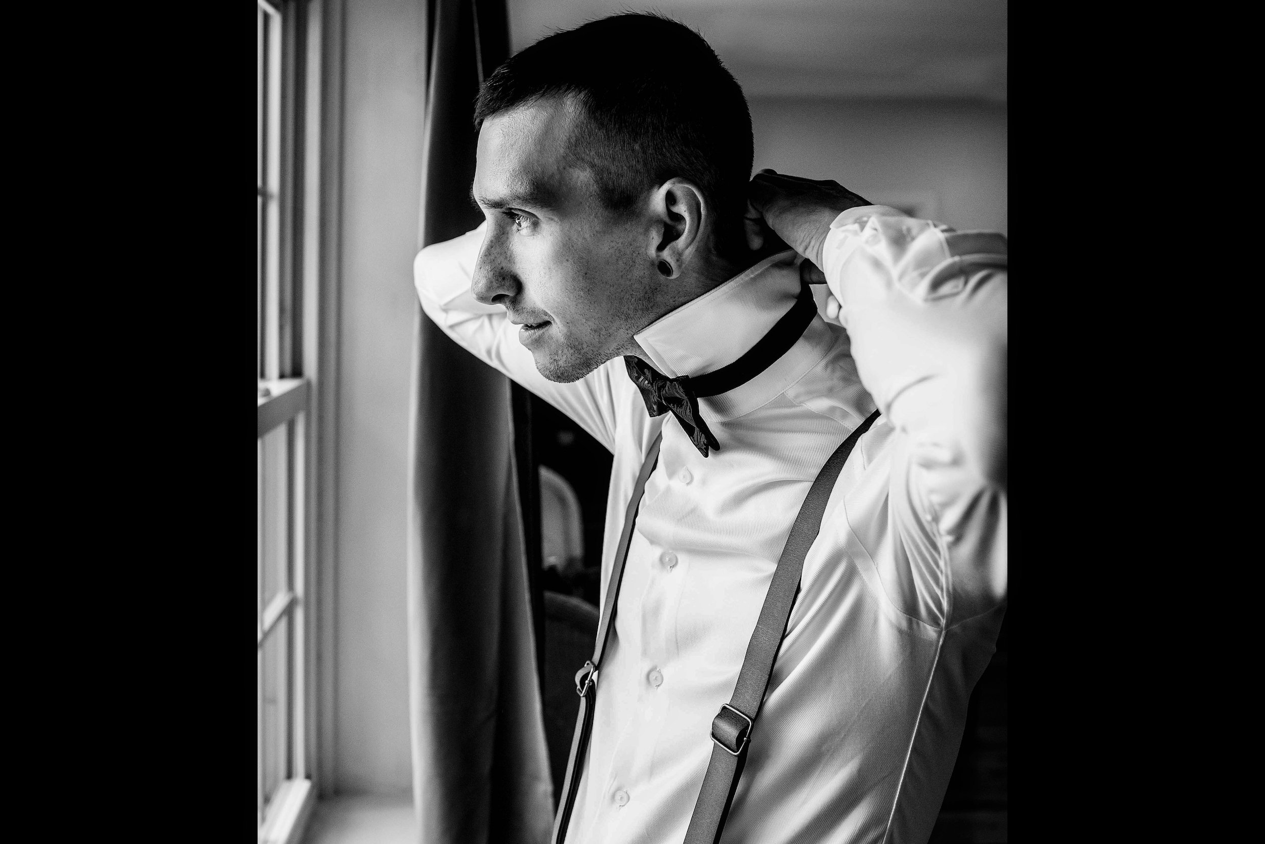 Groom putting on bowtie black and white