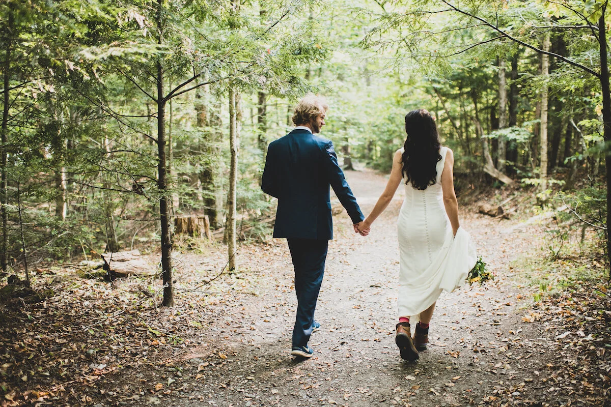 View of bride and groom walking away on hiking trail