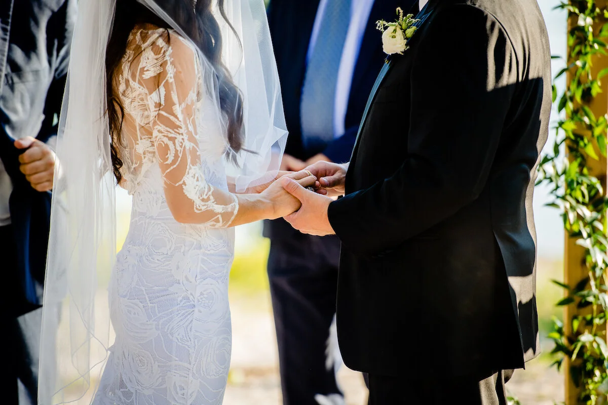 Close up of groom placing wedding ring on bride