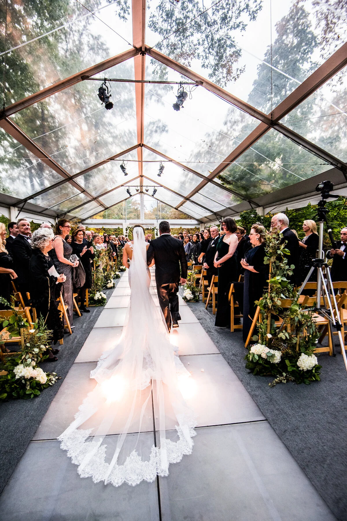 Bride and groom walk down the aisle of greenhouse venue