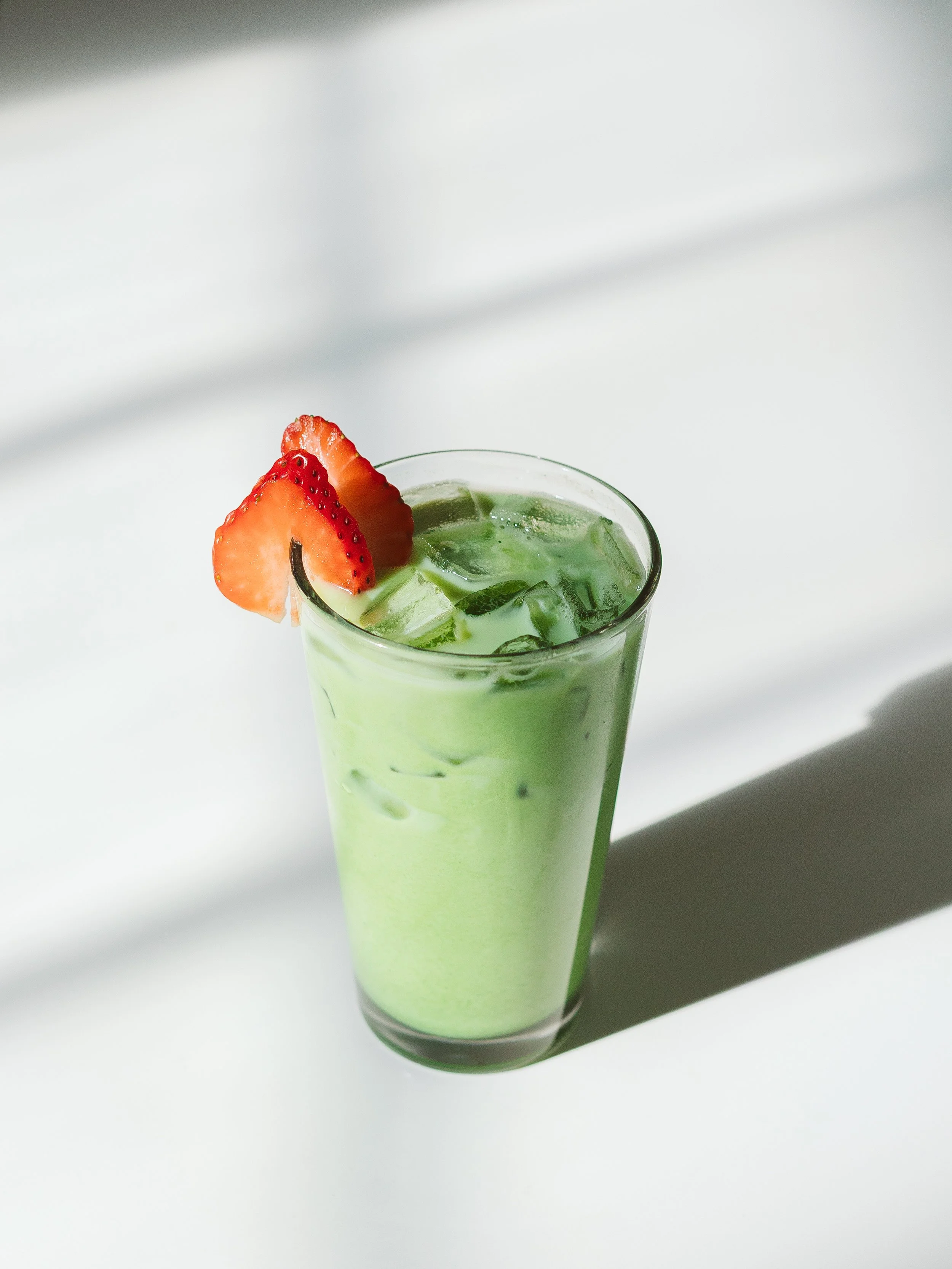 Iced Matcha Latte captured on a white table for a local Colorado Springs coffee shop. Coffee shop photography. Photo taken for Switchback Coffee. 