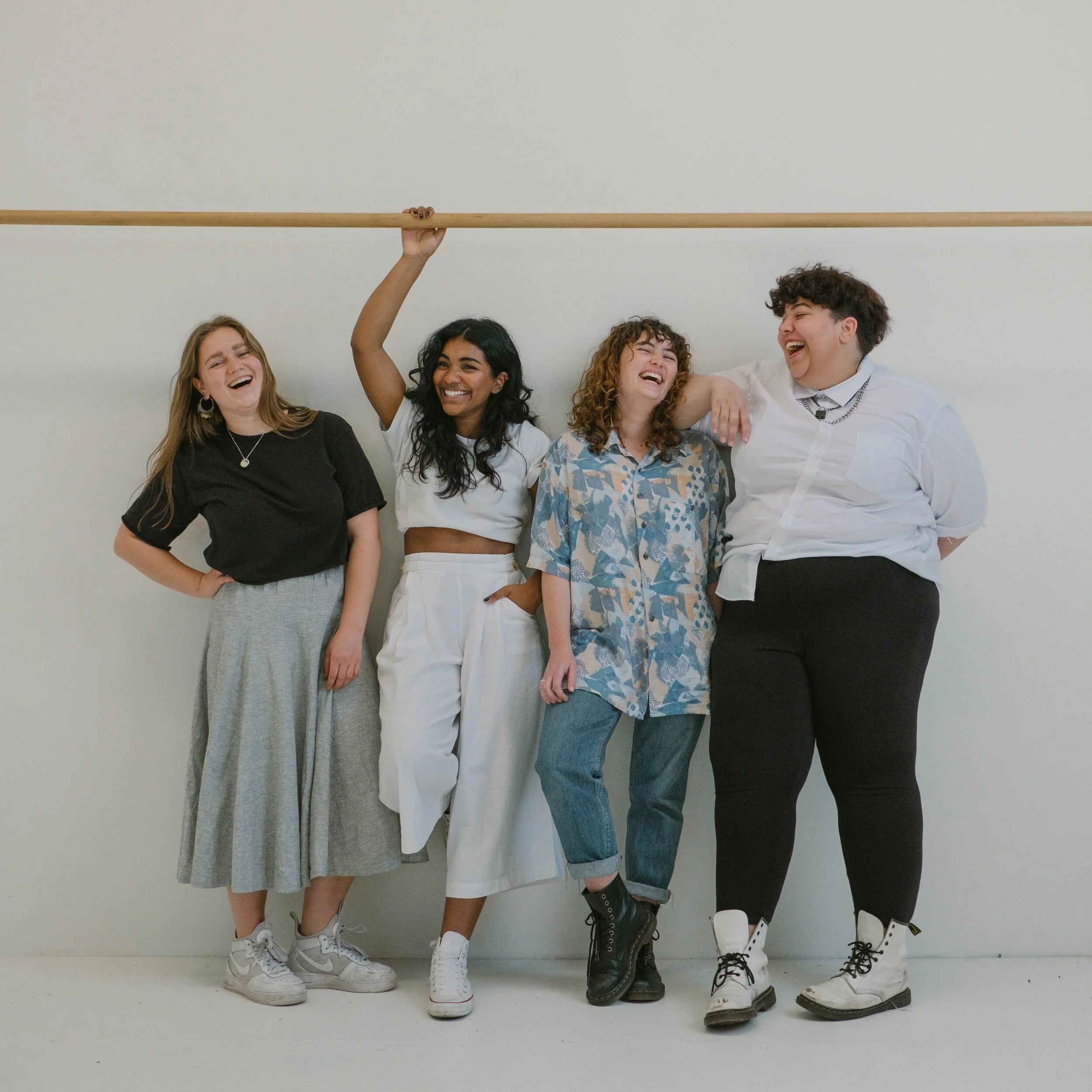 Group of four woman laughing on a white background