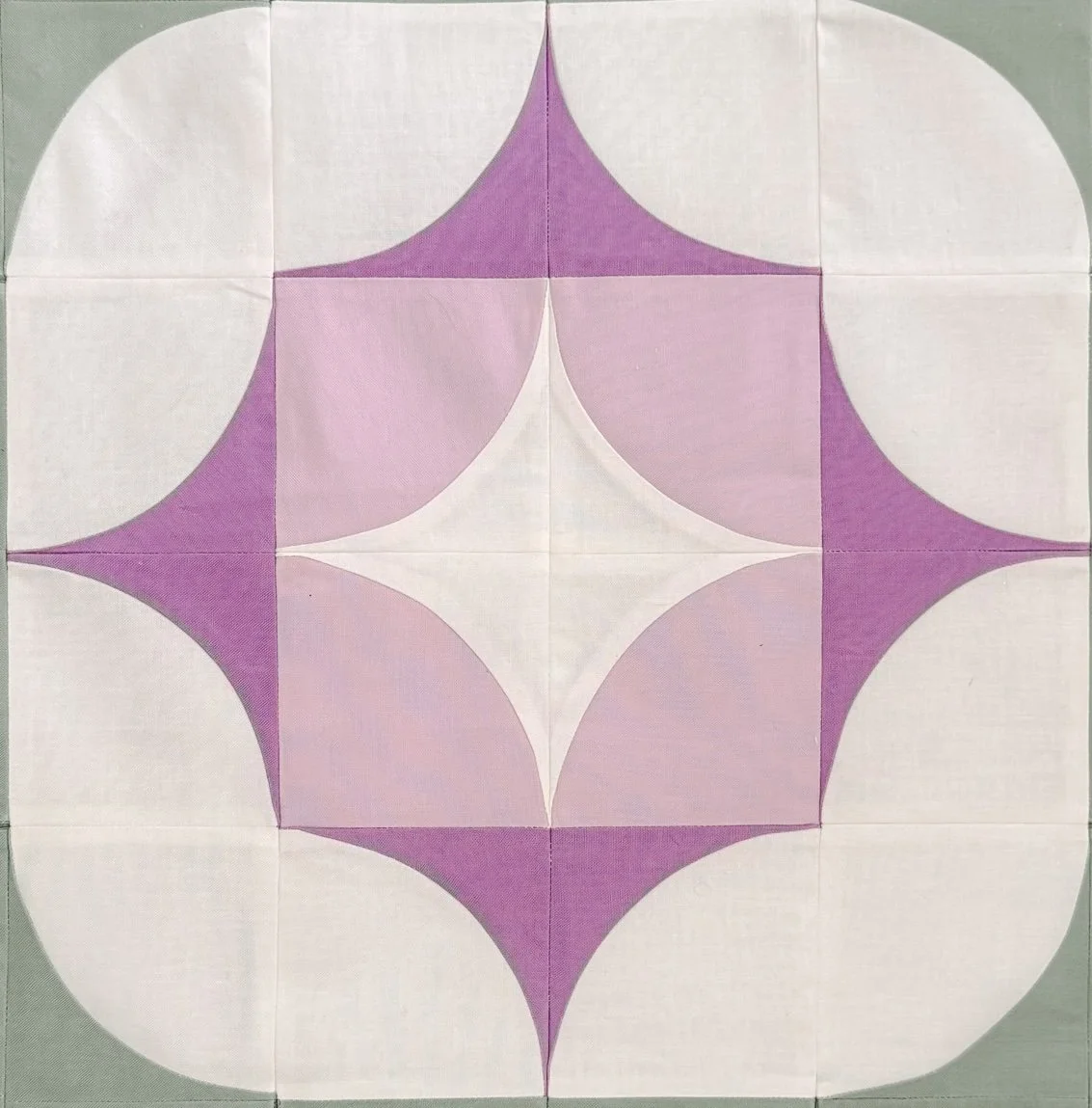 A geometric pattern featuring a central white diamond shape surrounded by purple and pink shapes forming a symmetrical design with curved edges on a tiled surface.