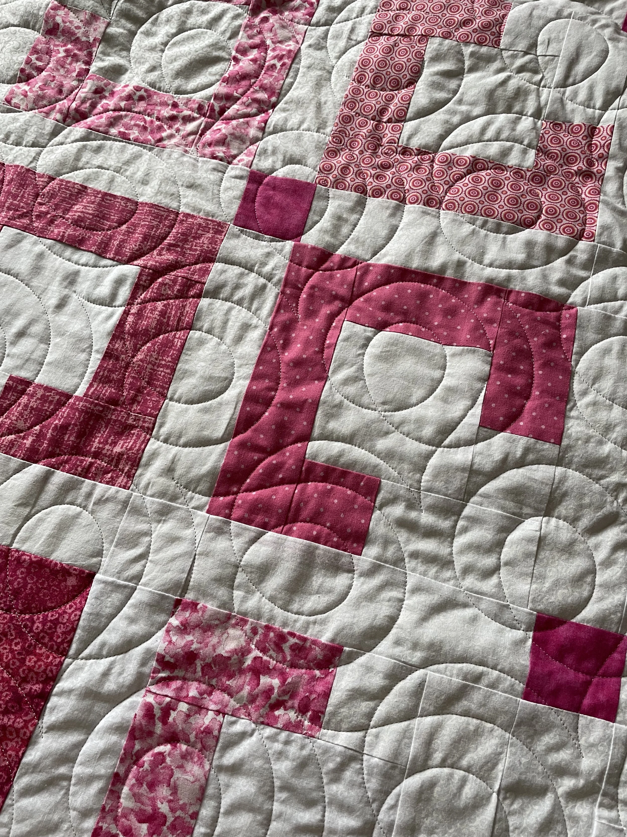 Close-up of a quilt with pink and white patchwork square designs.