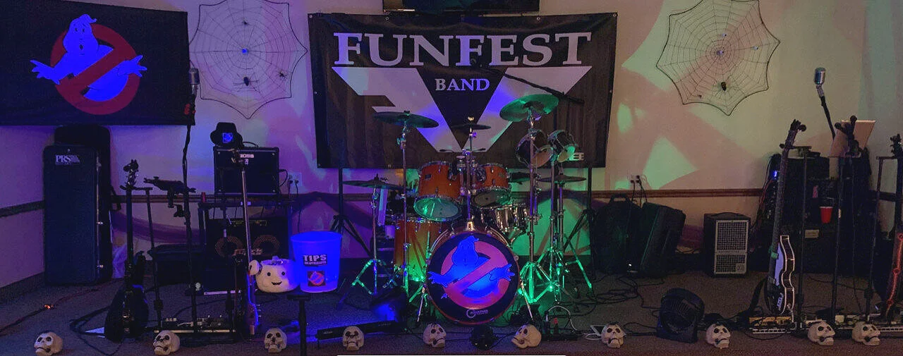 Funfest with Halloween decorations, including skulls and spider webs, and musical instruments such as drums, guitars, and amplifiers.