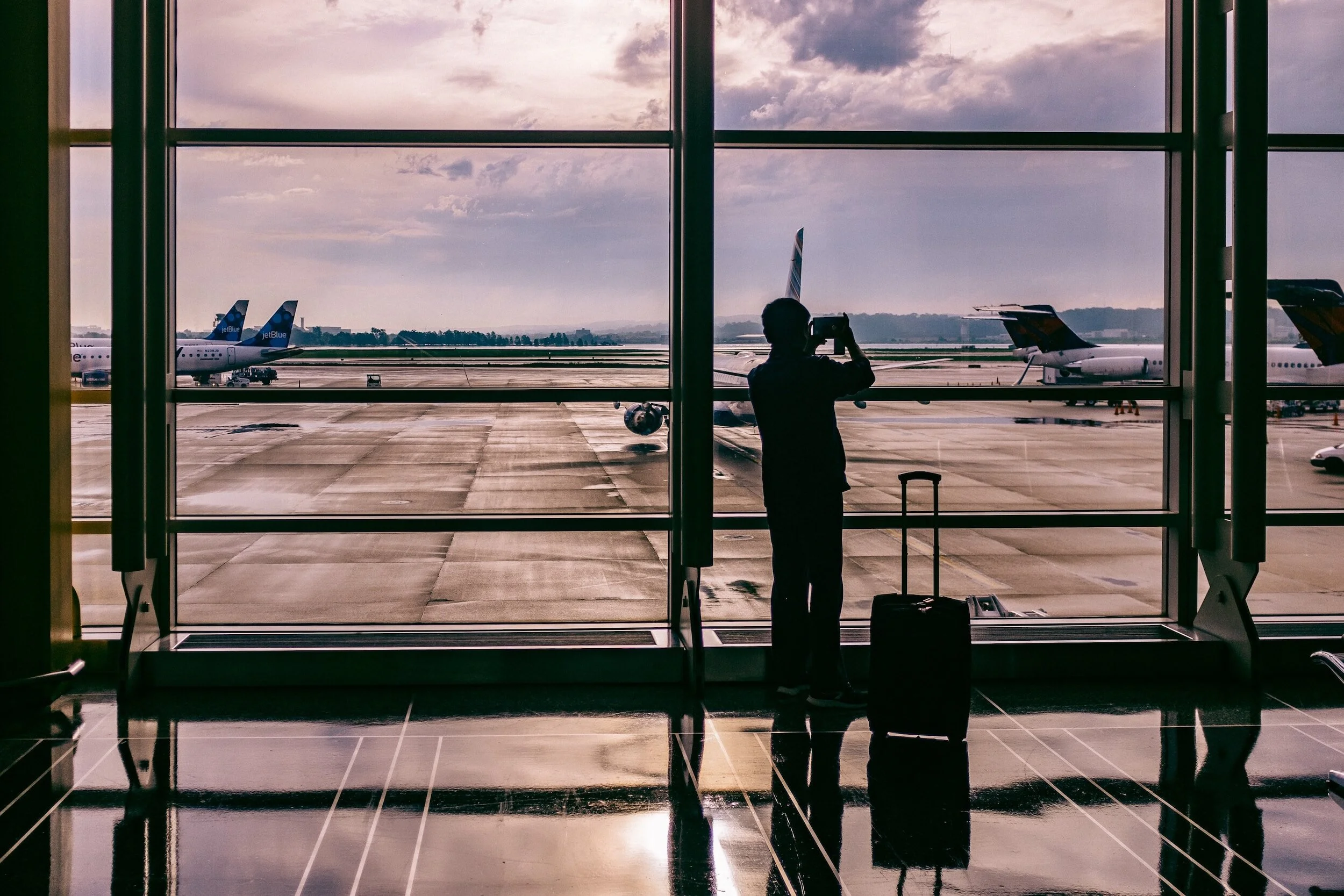 A man takes a photo of the tarmac on a rainy day.